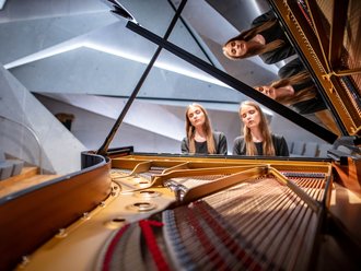 jugendliche Zwillingsmädchen gemeinsam am Klavier