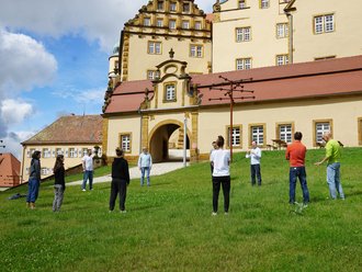 Menschen auf der Wiese vor einem Schloss