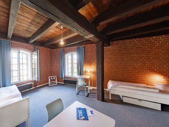 Raum mit 2 Betten und einer Sitzmöglichkeit