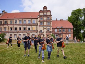 Kinder laufen über den Rasen vor der Akademie